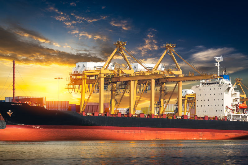 日落背景下装卸集装箱的工业船