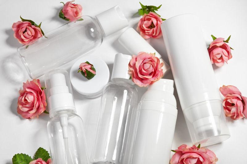 白色桌面上的粉色玫瑰画和白色化妆瓶