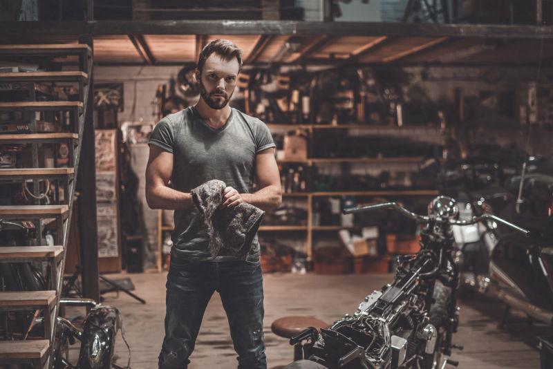 汽车修理厂里的男人和摩托车