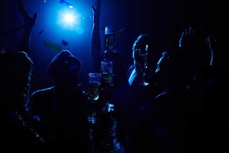 快乐的人在夜总会黑暗的灯火下喝酒