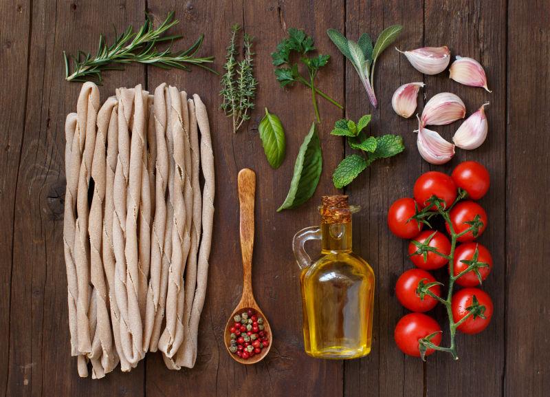 木制桌子上的面食蔬菜草本植物和橄榄油