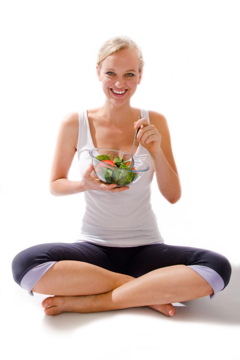白色背景上吃蔬菜沙拉的美女