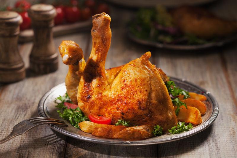 古董风景旧盘子里的烤鸡腿配烤土豆和蔬菜