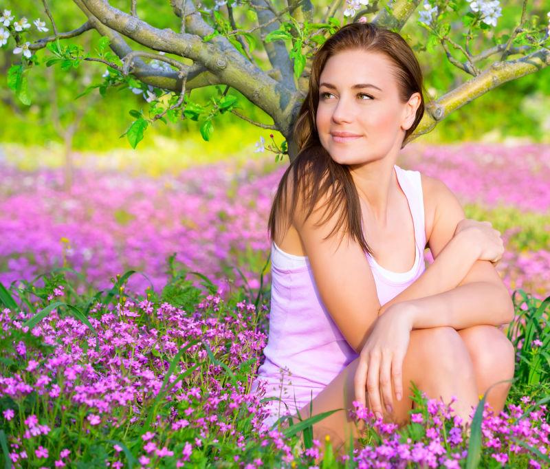 坐在开花的草地上的微笑的女子