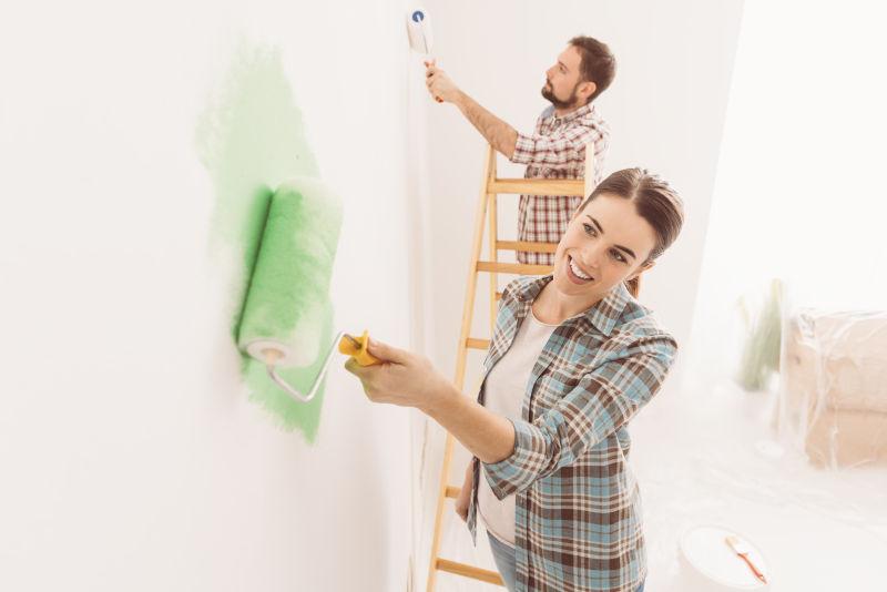 年轻的夫妇正在给墙壁刷油漆