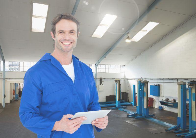 微笑机械师在车库里拿数字写字板