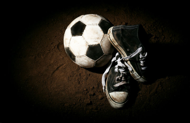 黑暗背景下的足球与鞋子