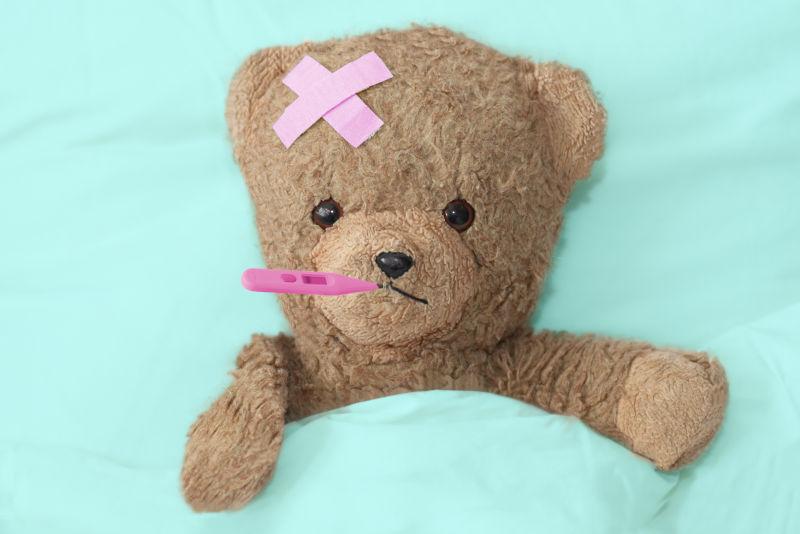 床上含着温度计的泰迪熊