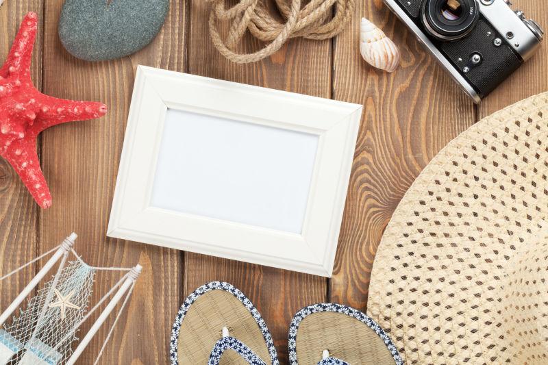 木桌上的凉鞋凉帽和老式照相机等旅行用品