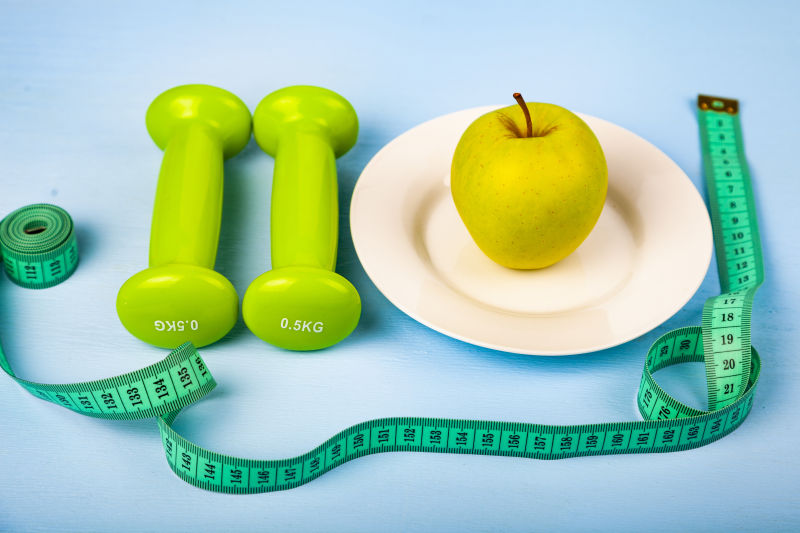 蓝色背景上的苹果哑铃和皮尺