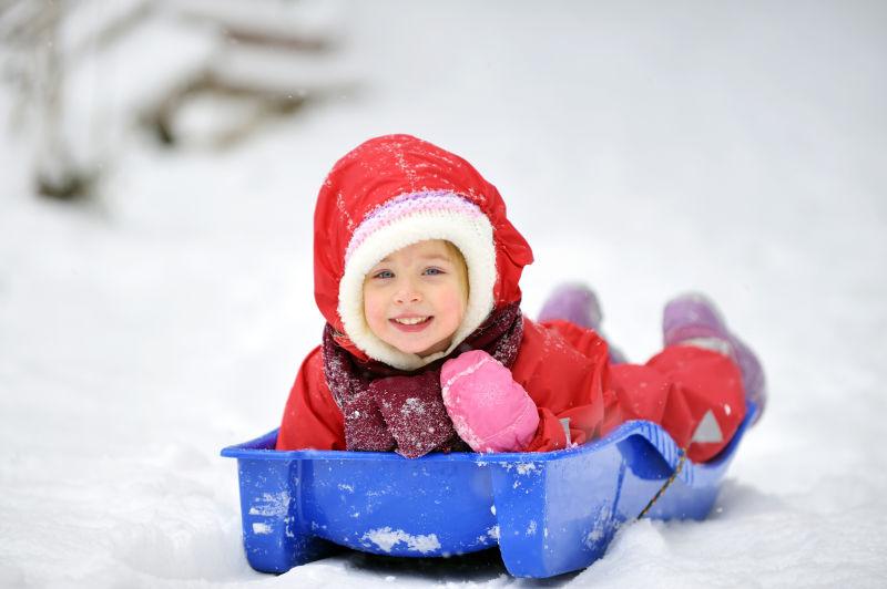 一个红衣服的孩子正在快乐的玩雪