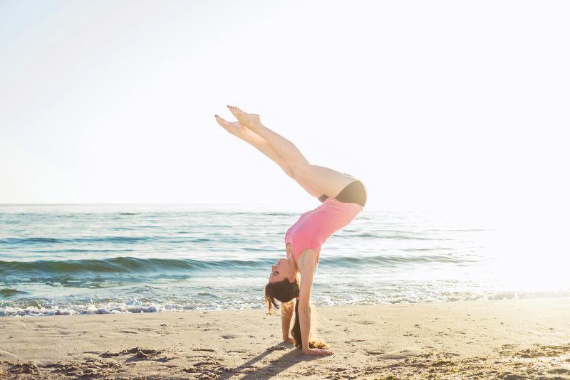 迎着阳光在沙滩上做着瑜伽的女人