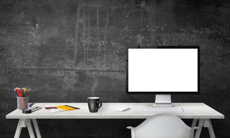 黑色墙面下放着电脑的白色办公桌