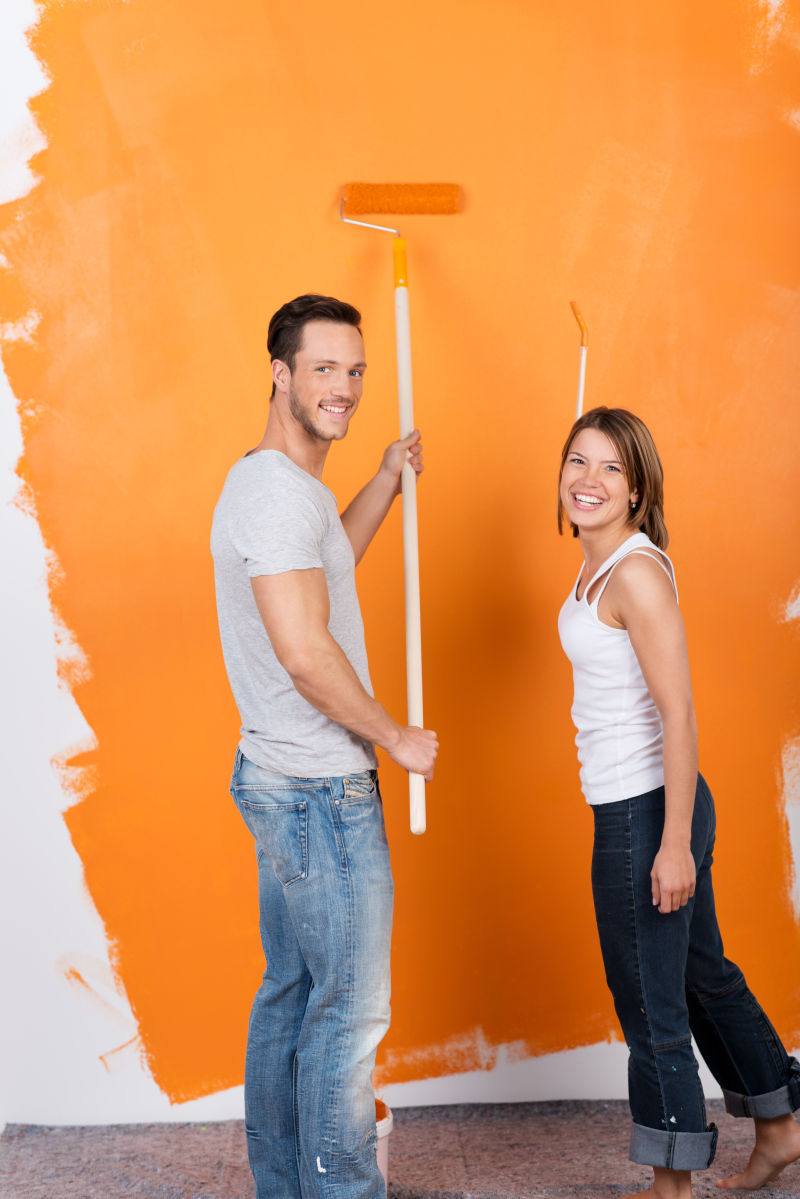 一起进行墙壁刷漆的年轻夫妇