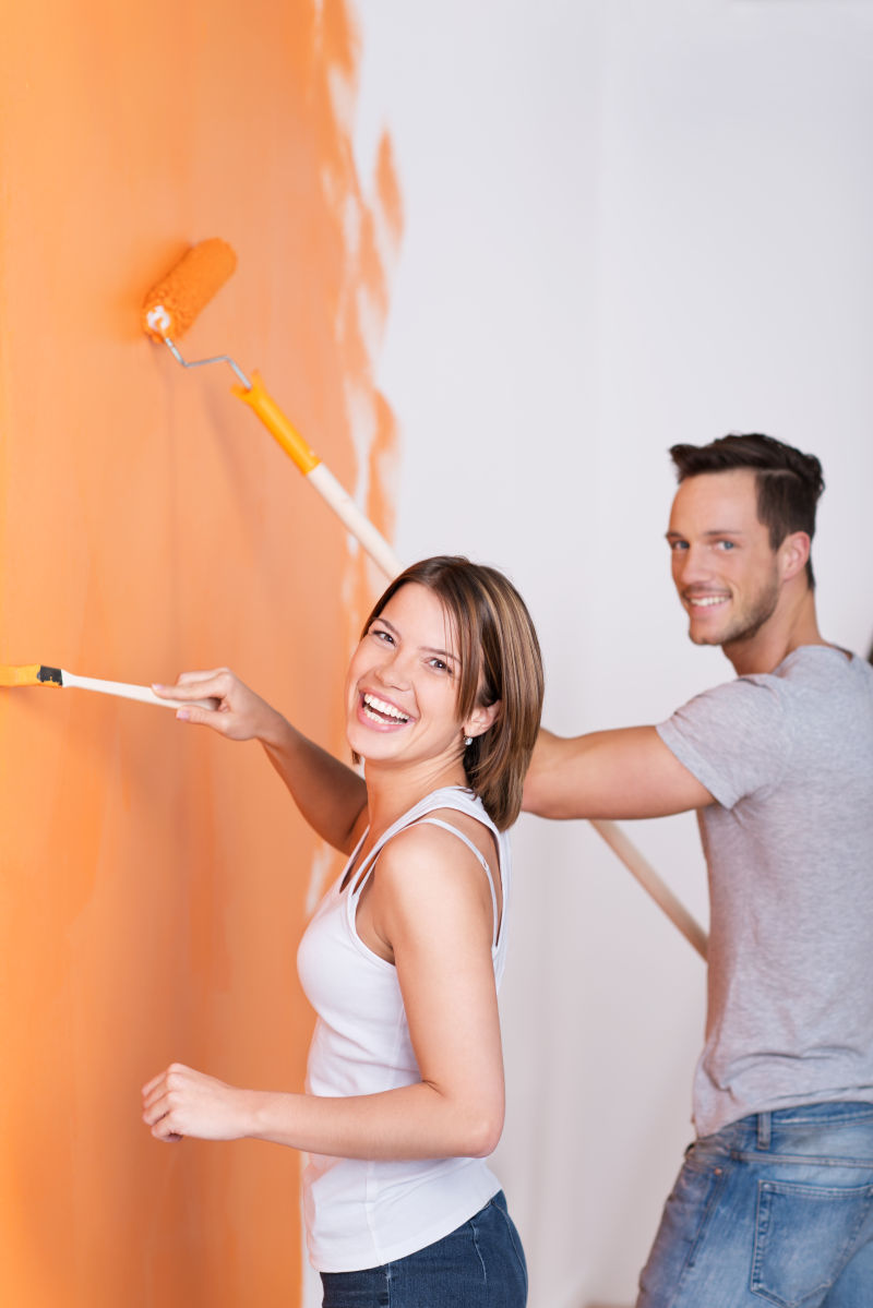正在进行墙壁刷漆的快乐年轻夫妇