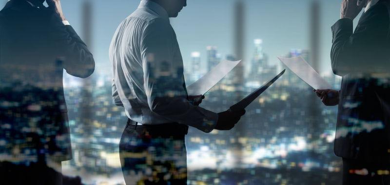 城市背景下的拿文件的商人的双重曝光