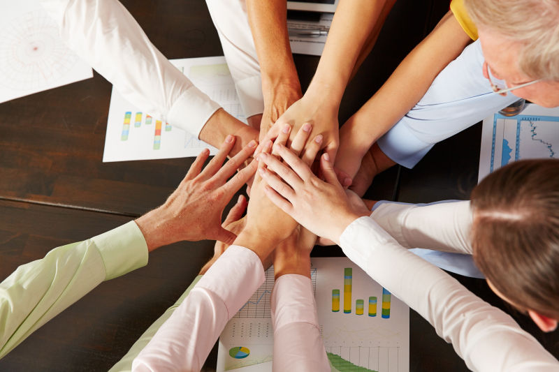 办公桌上将手交叠在一起的商务团队