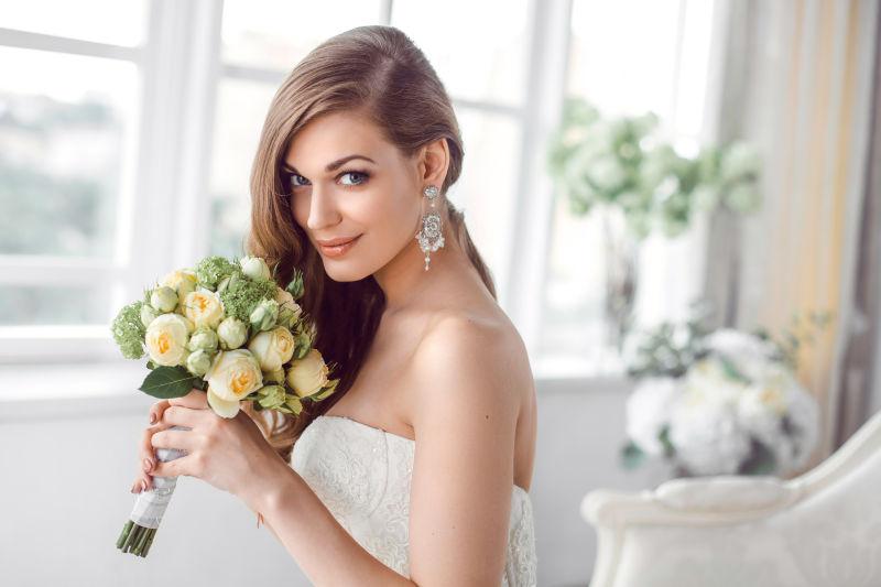 时尚美丽的新娘拿着手捧花坐在沙发上