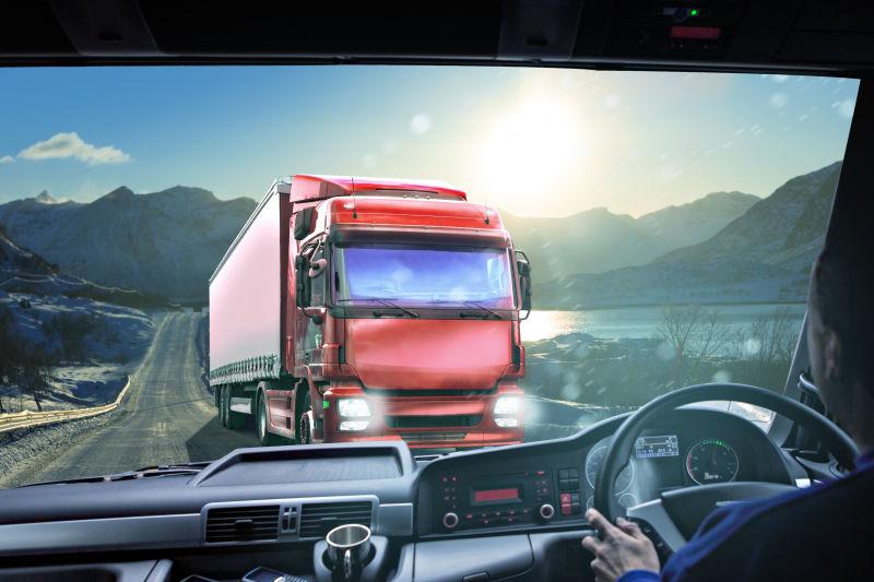 群山和阳光的背景下的公路上的红色卡车