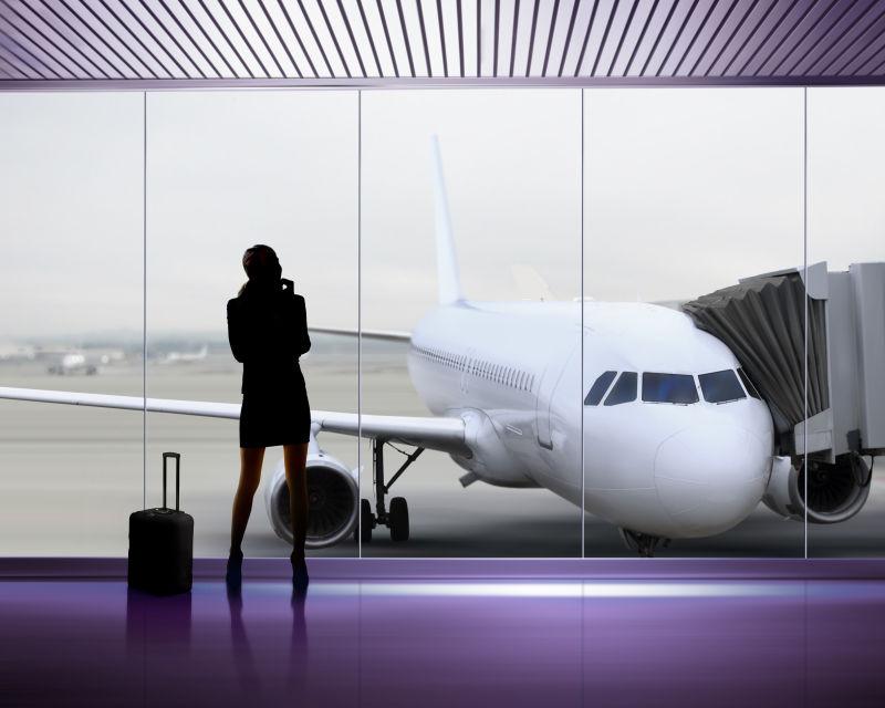 白色飞机背景下有落地窗的机场候车室里候机的女人剪影