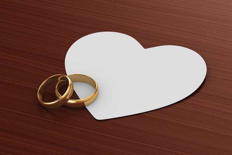 心形剪纸上的黄金对戒