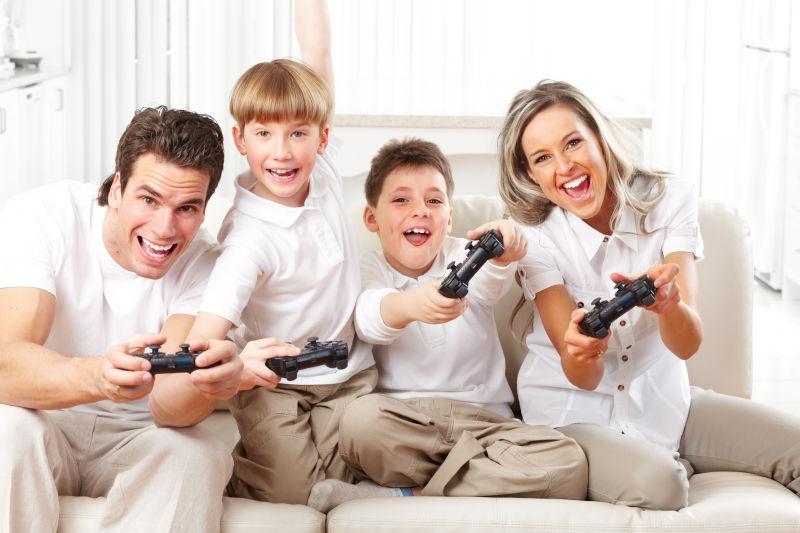 白色背景上坐在沙发上玩游戏的一家四口