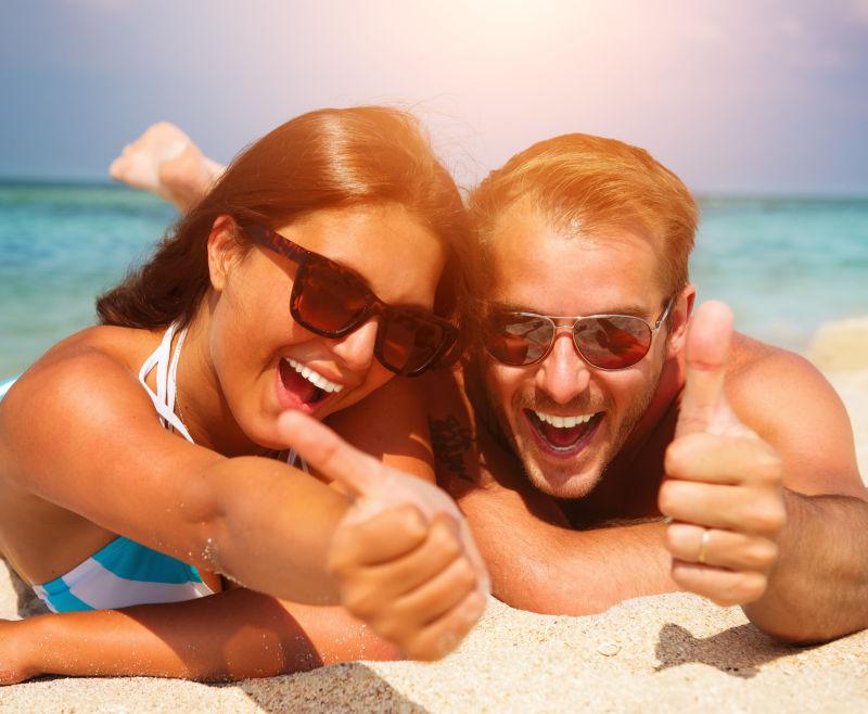 沙滩上竖着大拇指的情侣