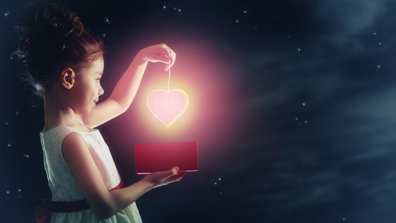 拿着发亮心形灯光的女孩