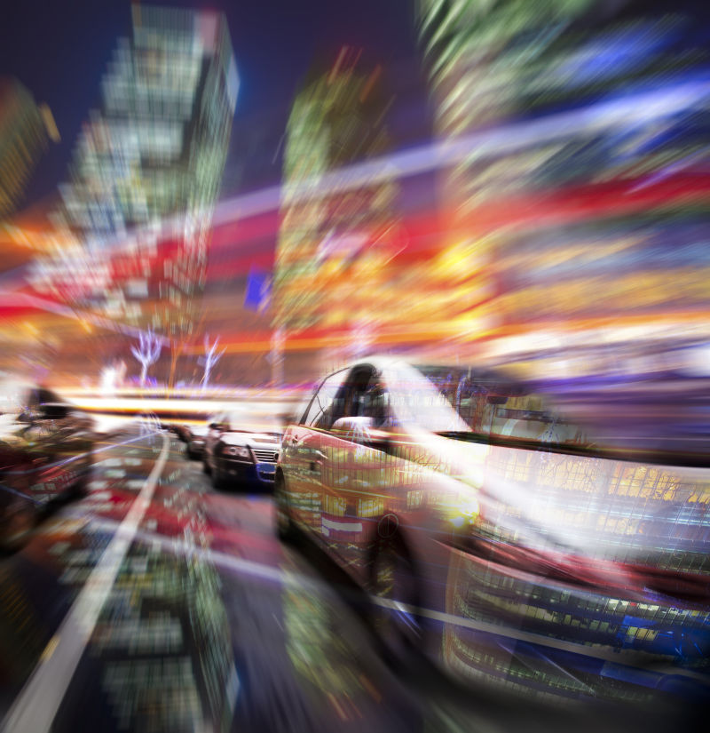 模糊大厦的背景下在夜间行驶的汽车