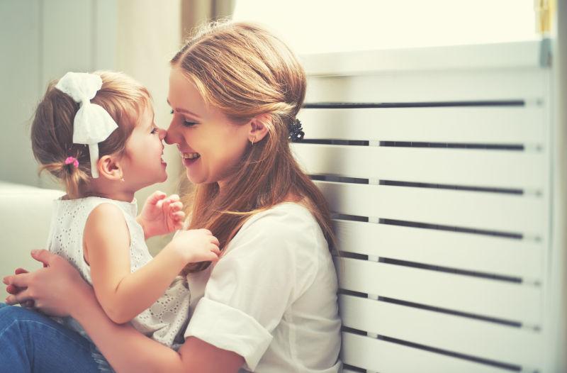 触碰怀里女儿鼻子的母亲