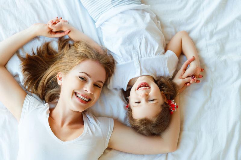 躺在白色床单上的金发母女