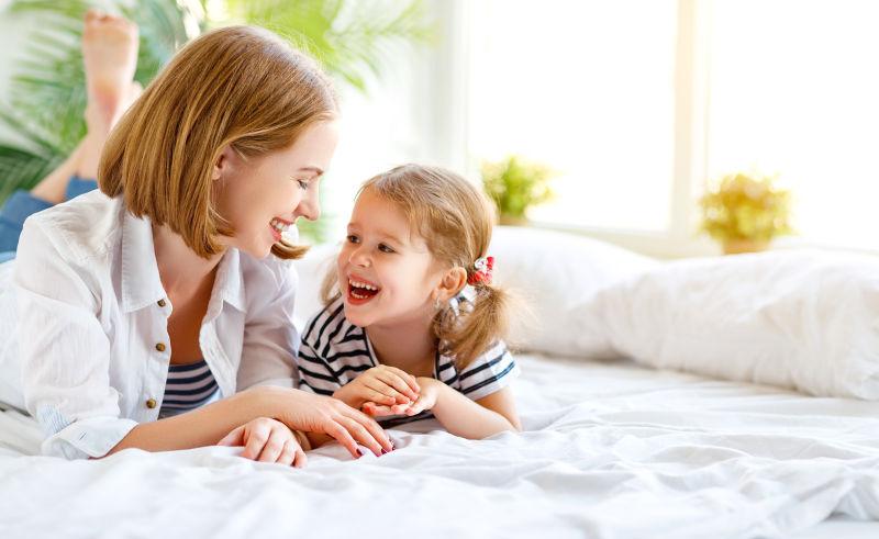 趴在白色床上的快乐母女