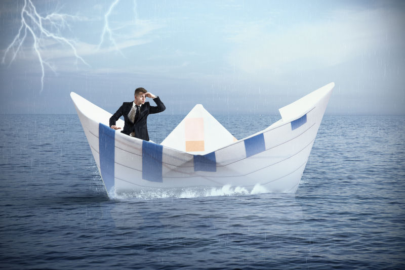 风暴下坐在纸船上的男人
