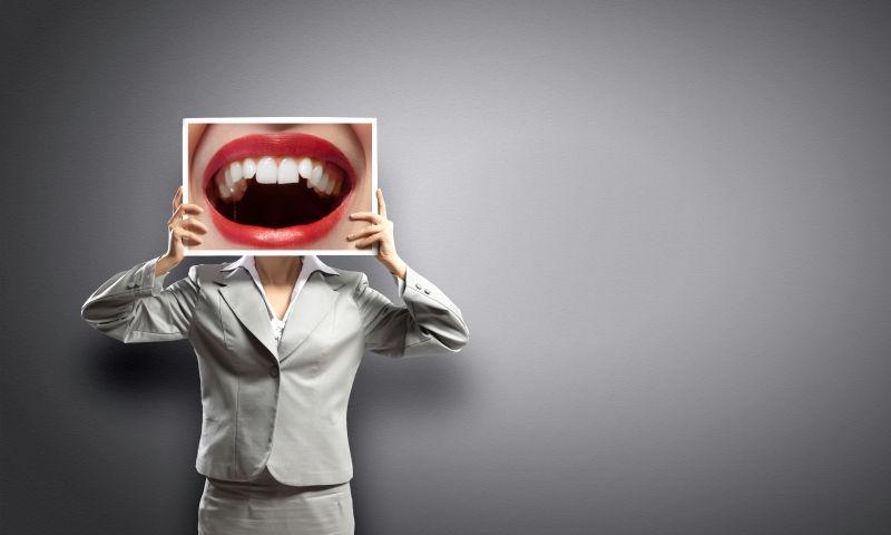 灰色背景中举着红唇封面的女人