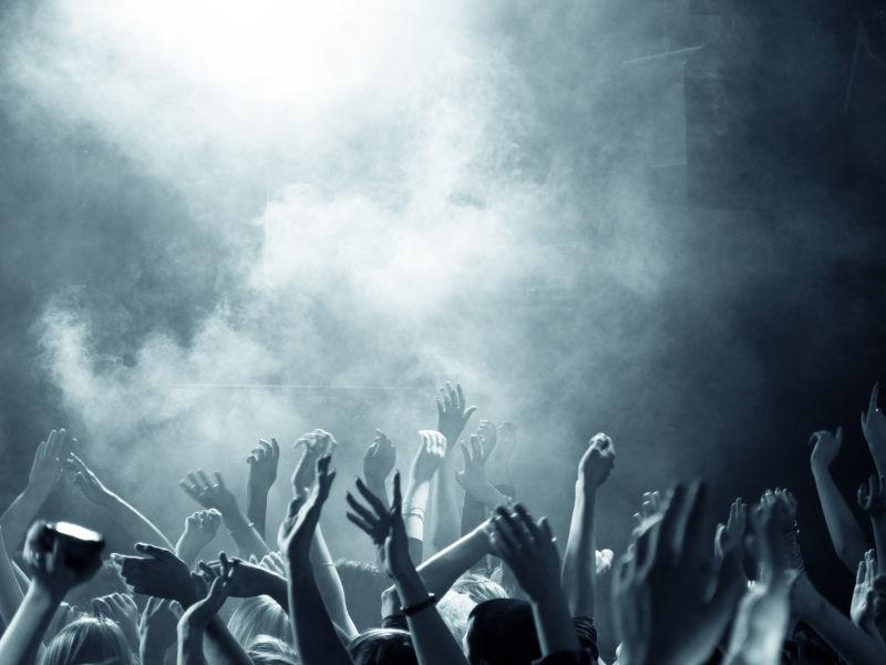 烟雾灯光下挥舞手臂的人群