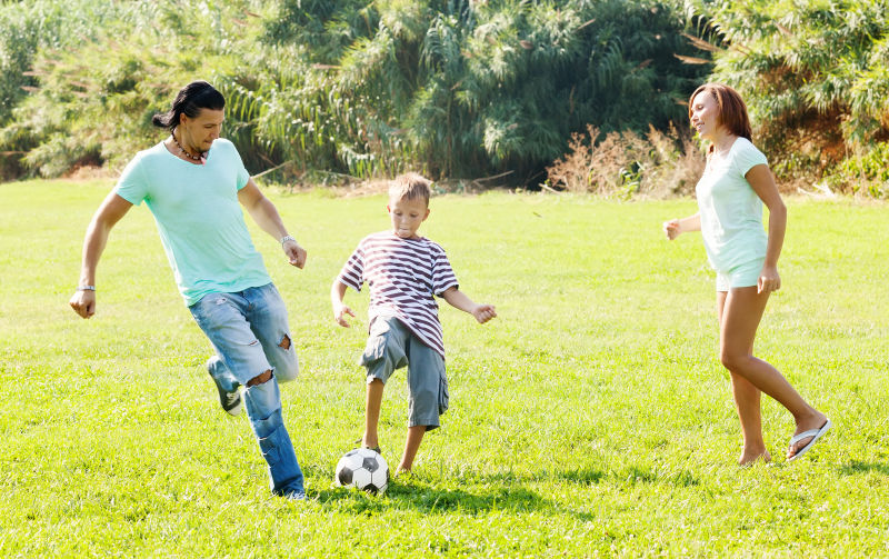在草地上踢球的一家人