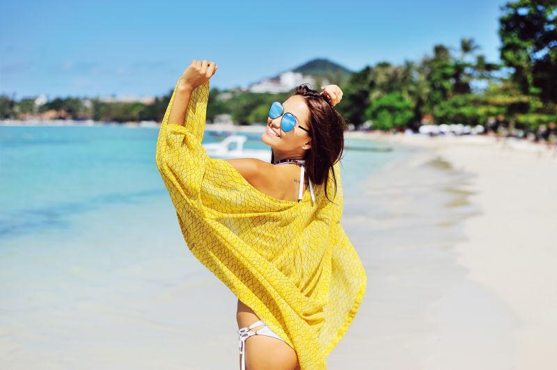 穿着比基尼泳装的年轻漂亮女人在沙滩上摆姿势