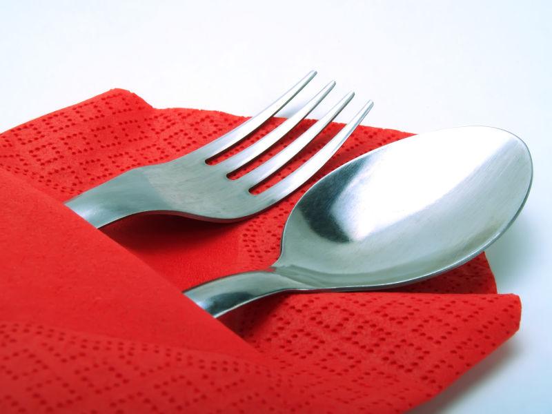 白色背景上红色餐布里的叉子和勺子