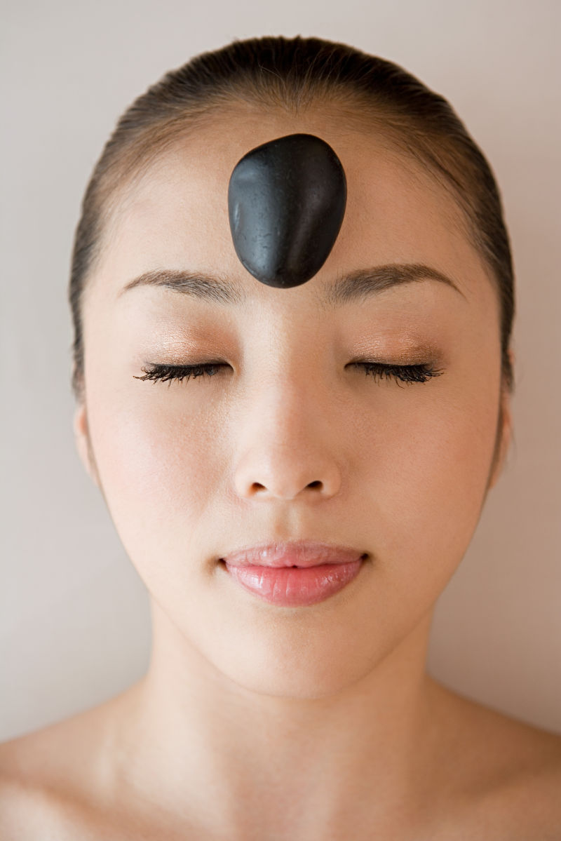 闭着眼睛的美女额头上放着一颗黑色石头