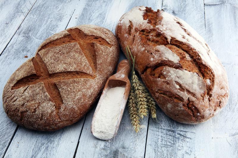 木桌上的两个小麦面包和面粉