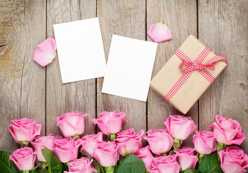 在木桌上礼品盒和粉红玫瑰