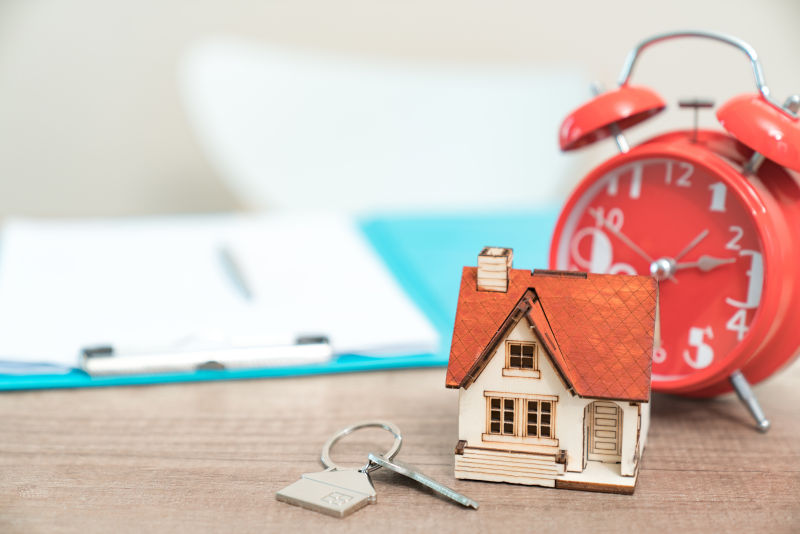 家用钥匙和红色闹钟房地产概念