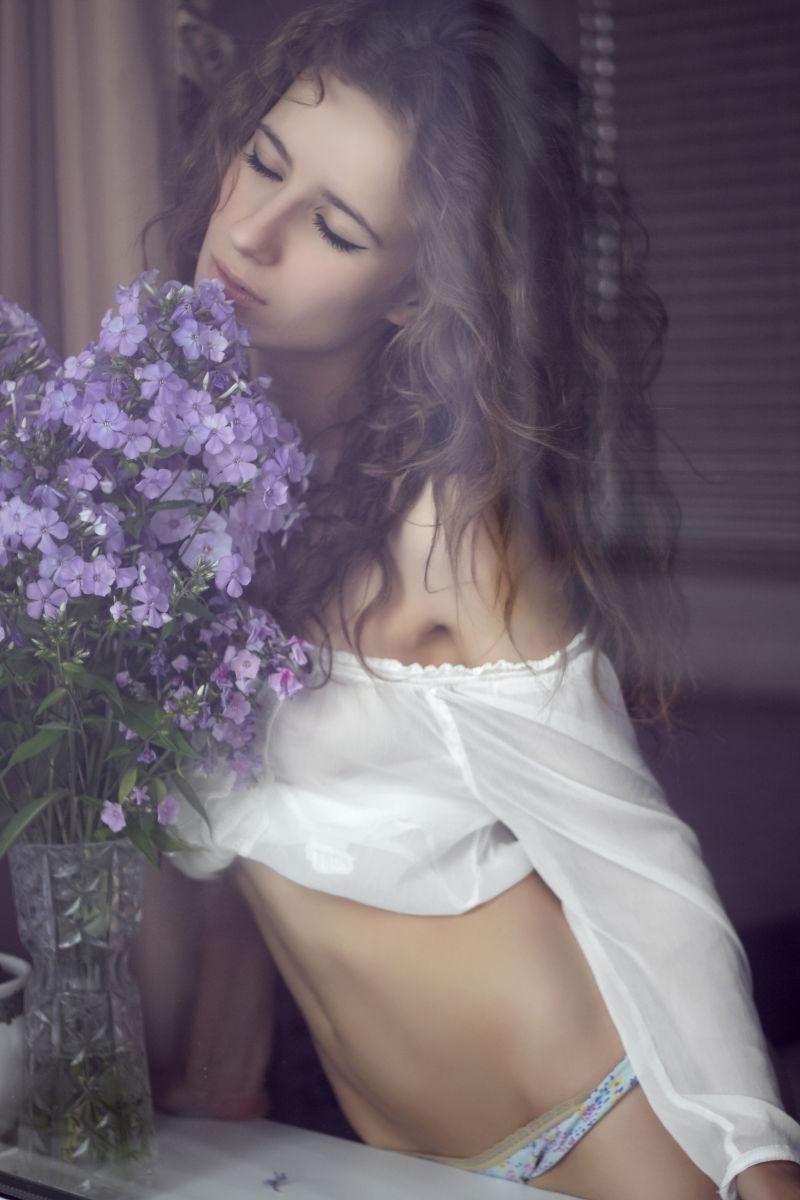 窗户边闻着花香的美女