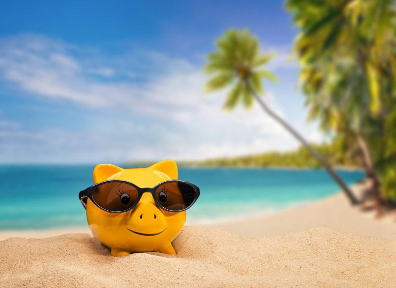 沙滩上带着太阳镜的黄色小猪存钱罐