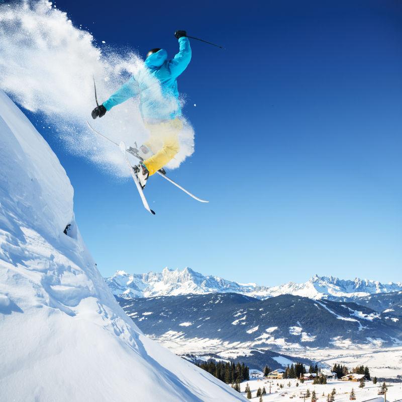 晴天群山背景上的跳跃滑雪者
