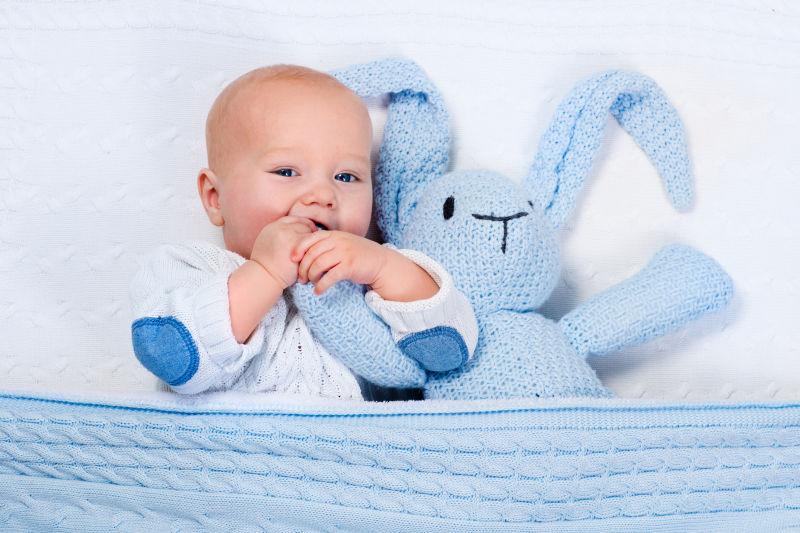 躺着玩玩具兔子的小婴儿