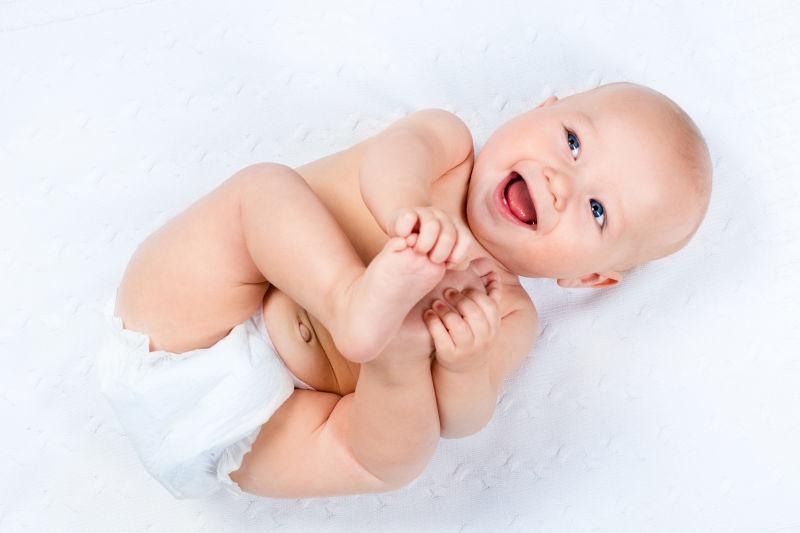 白色背景中带着纸尿裤微笑的新生儿