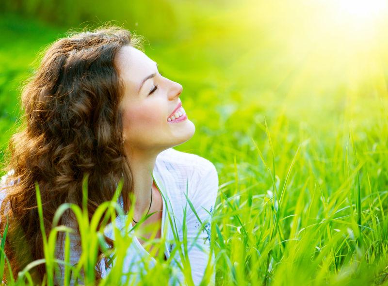 阳光下趴在草地上微笑的美女