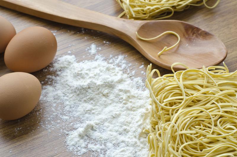 桌子上的面条鸡蛋面粉与勺子