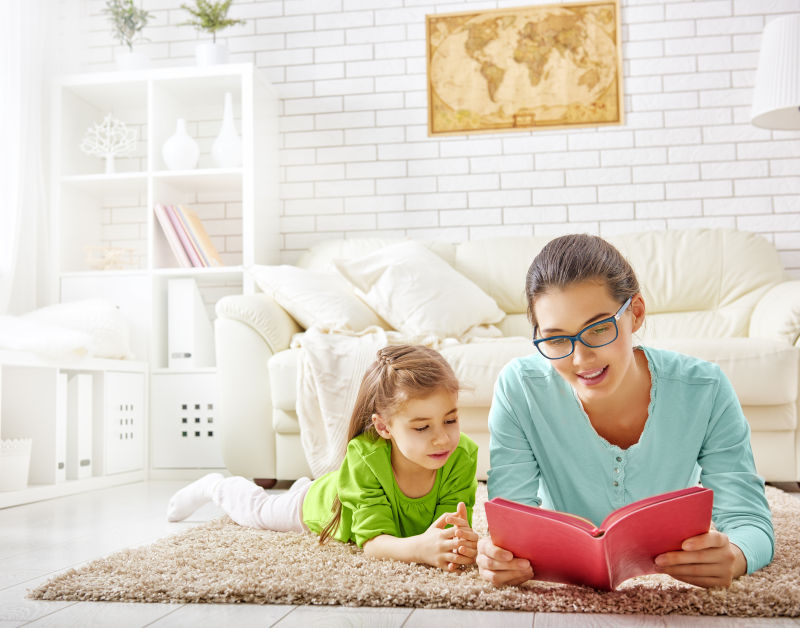 趴在毛毯上给女儿讲故事的母亲